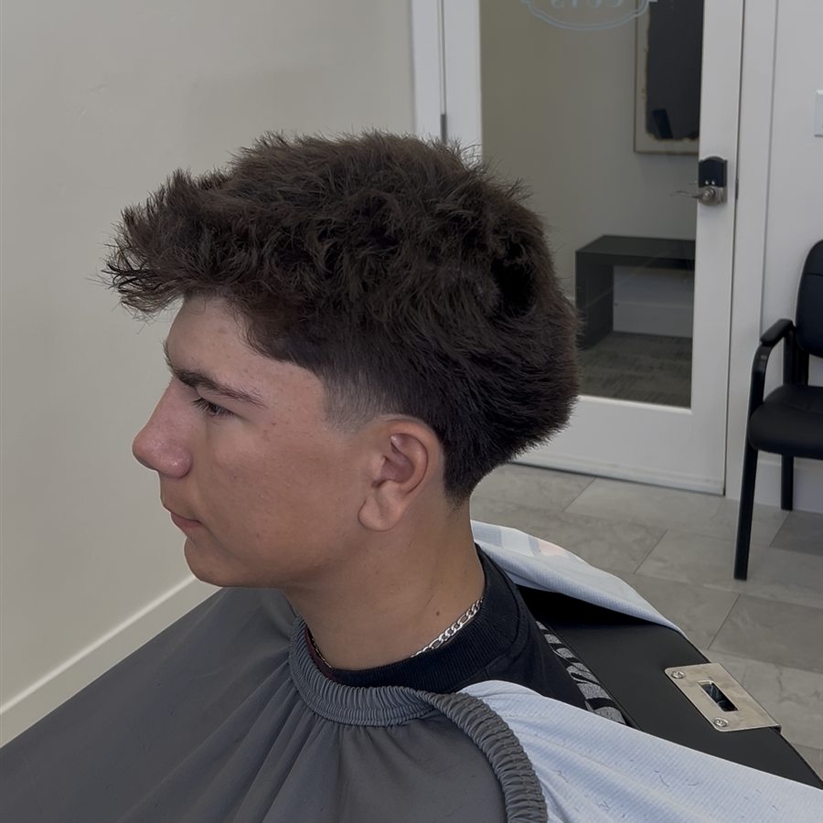 Client haircut with textured top and tight fade, left profile